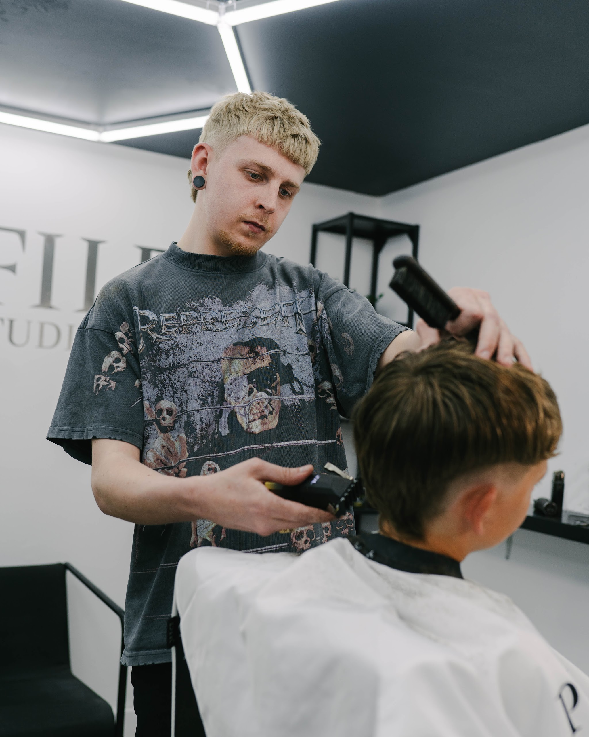 A barber clipper-cutting a boy's hair in the studio