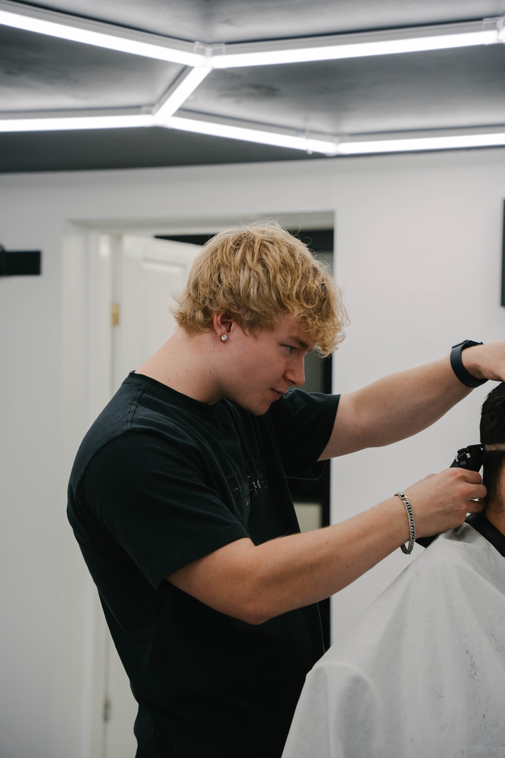 A barber using clippers under the LED ceiling