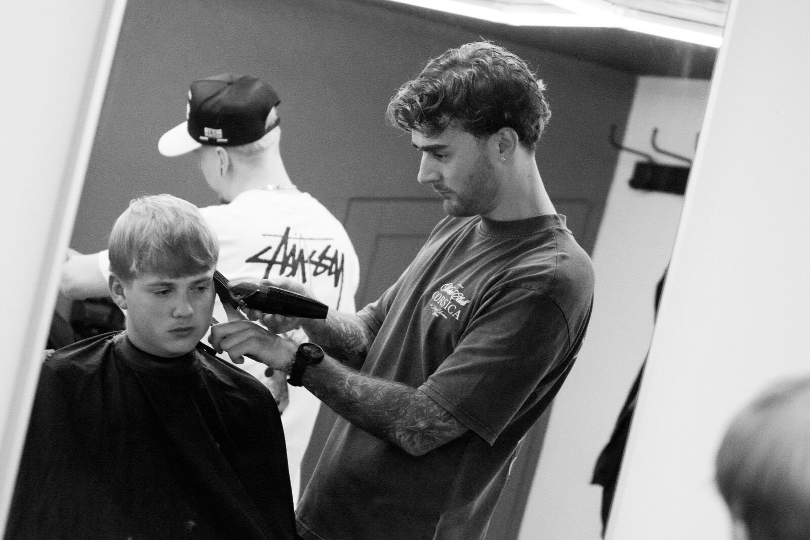 Black and white photo of a barber cutting a young client's hair