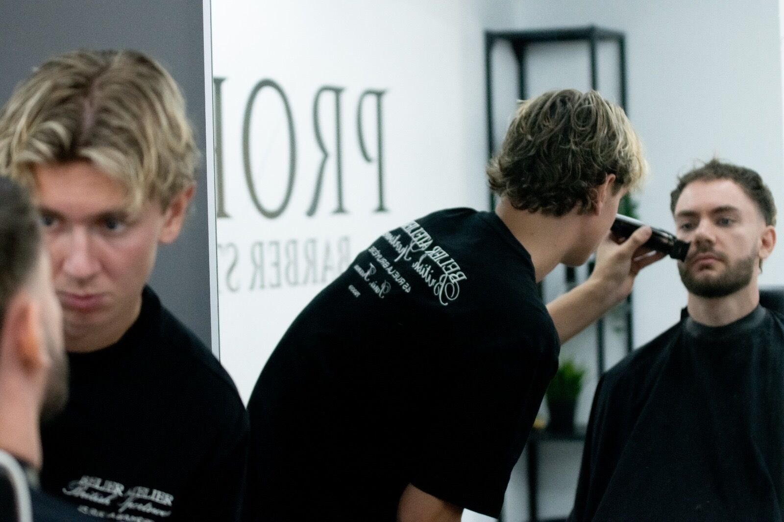 A beard trim in front of the mirror, with the Profile sign reflected behind