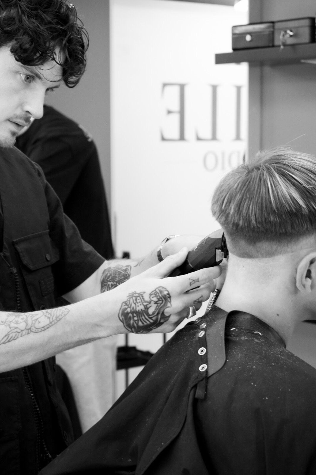 Black and white close-up of a fade being worked in at the back of the head