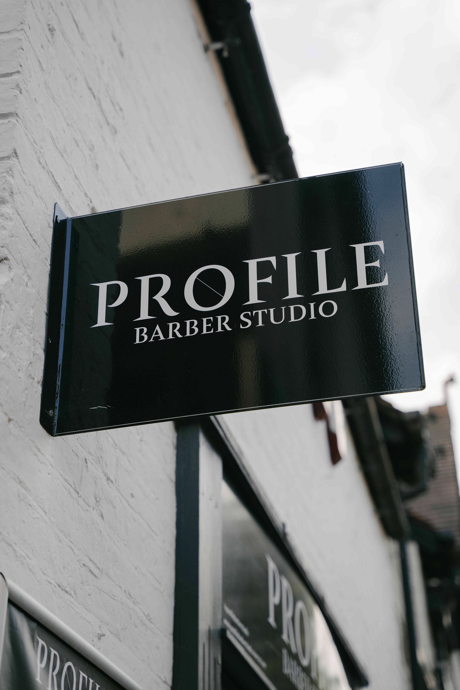 The hanging Profile Barber Studio sign outside the shop