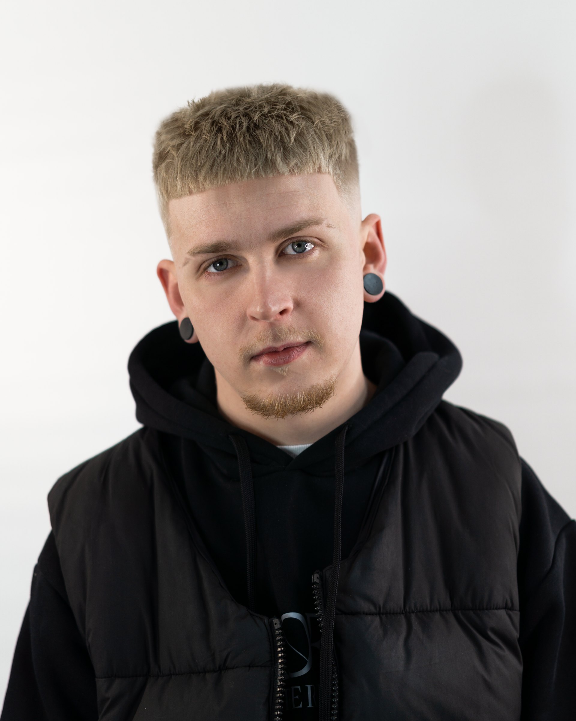 Studio portrait of one of the Profile team in a black hooded jacket